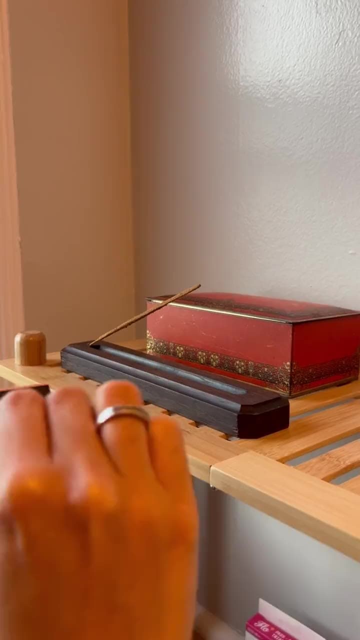 A match lighting incense on a small wooden holder