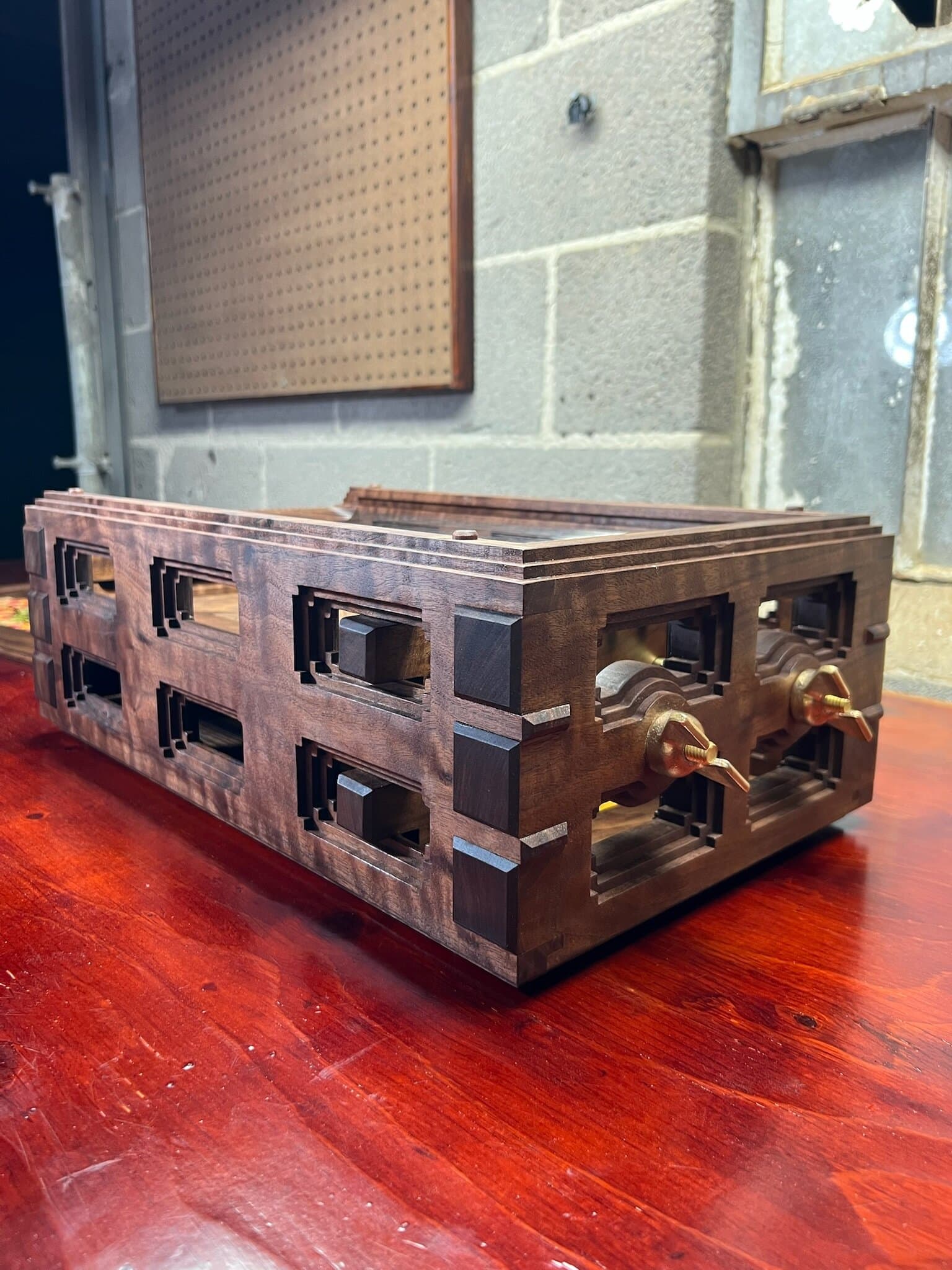 The chitarra from one end, brass tuning pegs set into its walnut frame