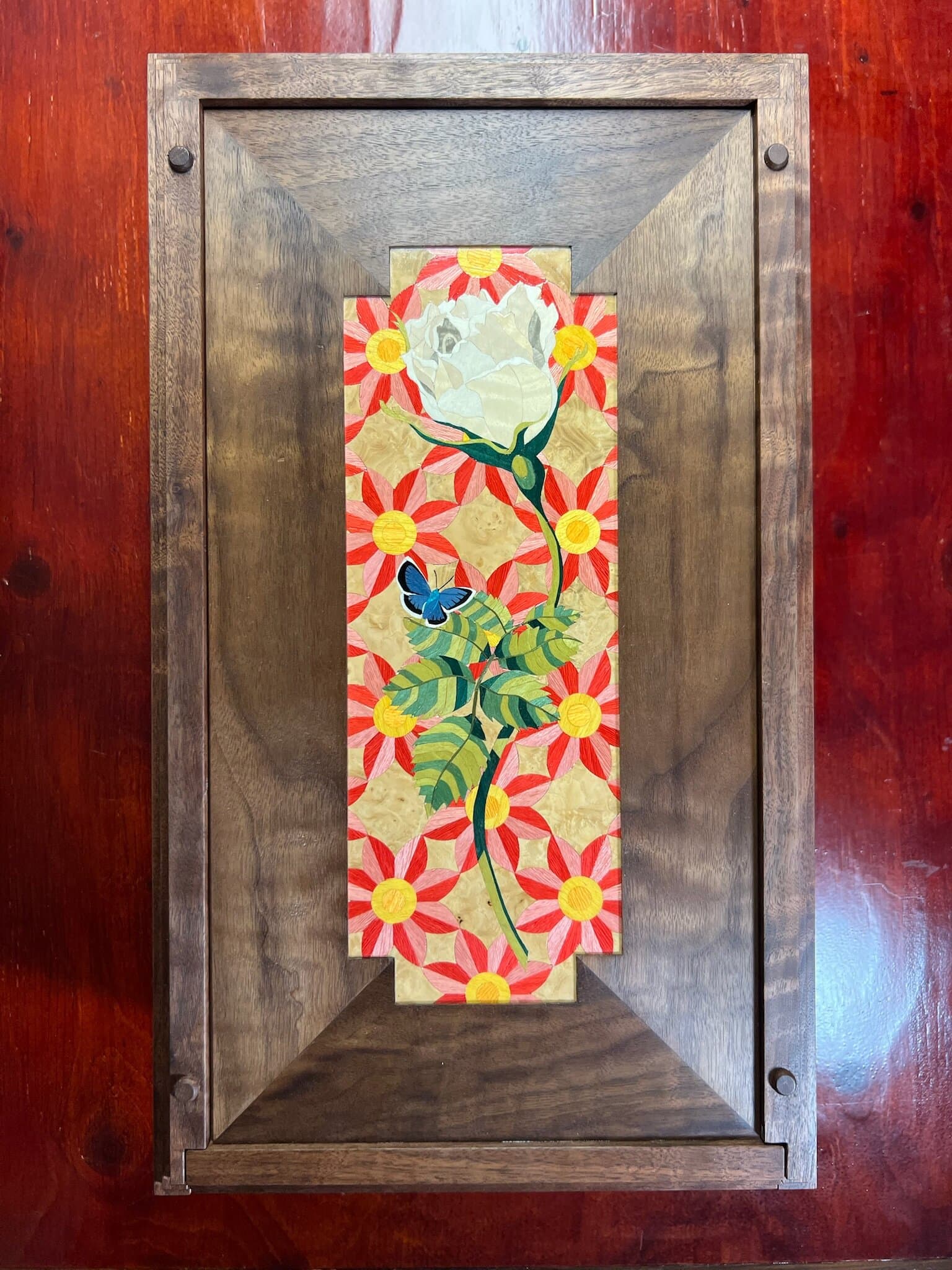 Marquetry panel of a white rose and a blue butterfly set into the walnut lid