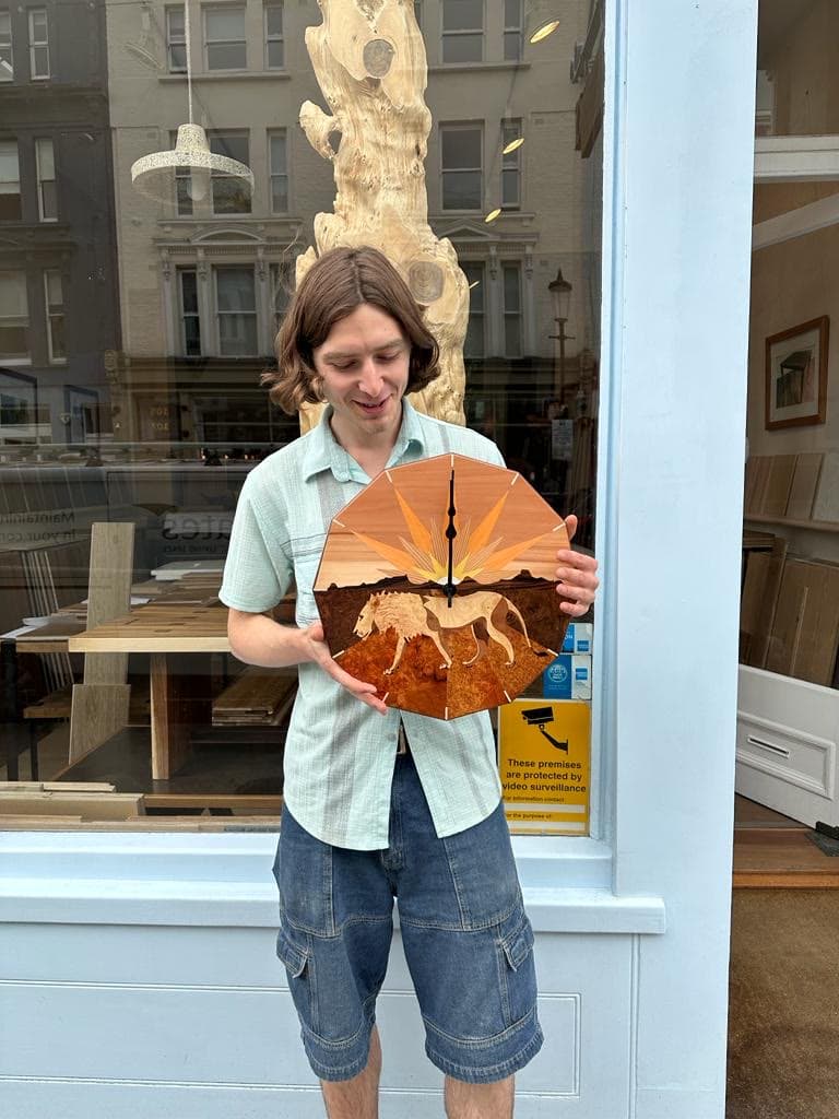 Louis holding the finished clock outside the workshop's shopfront