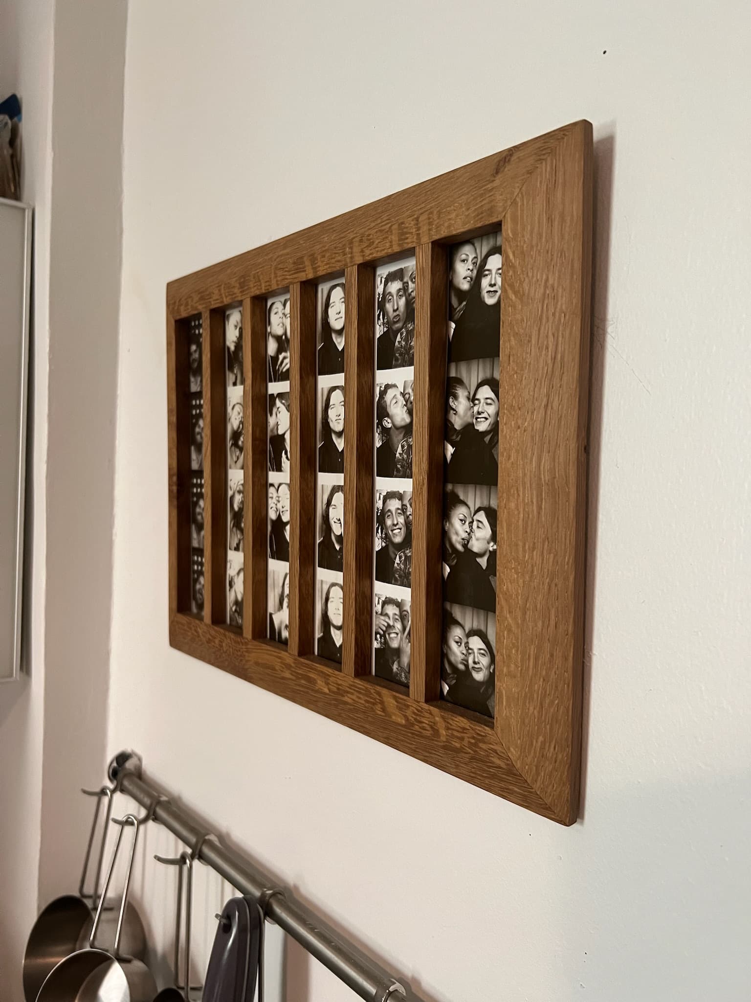 Oak frame holding six photo-booth strips, hung on a kitchen wall