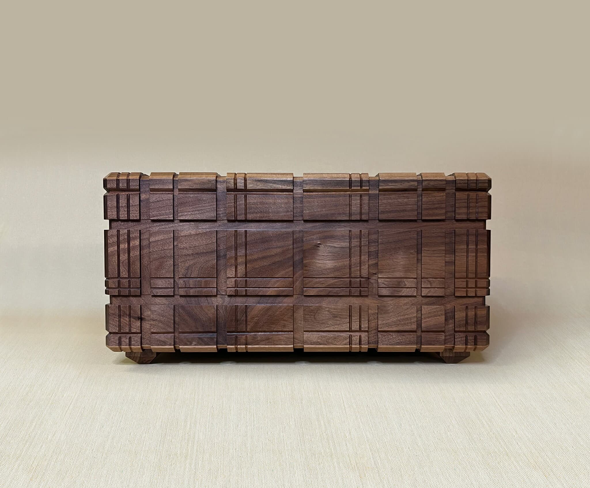 The puzzle box straight on, tartan grooves running across its walnut front