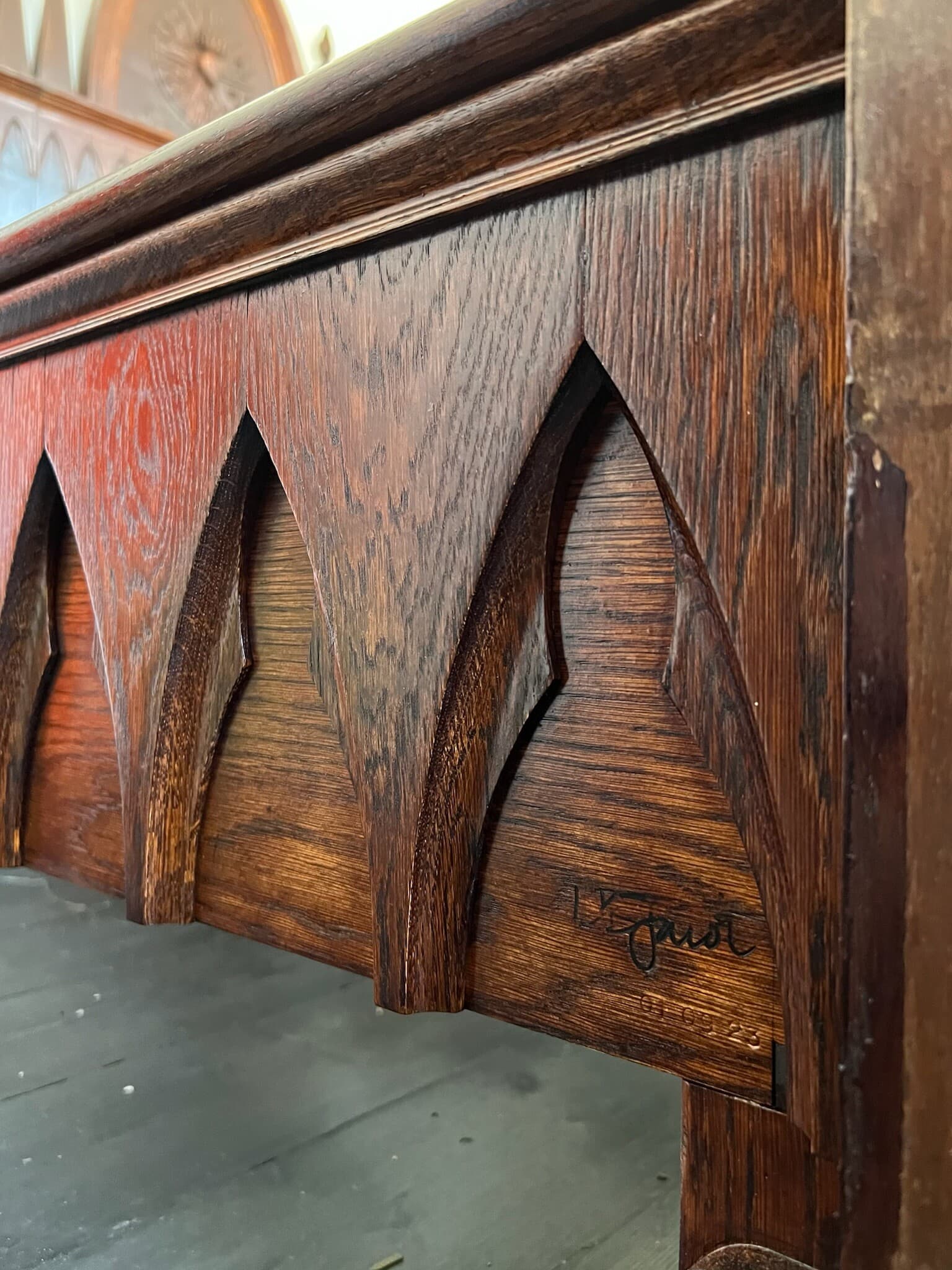 The side rail's pointed arches up close, signed at the corner