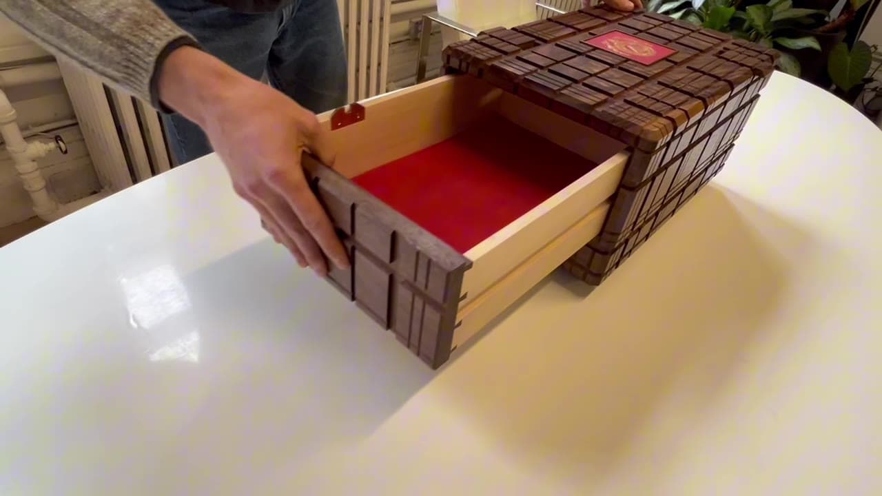 The puzzle box being solved, its drawer sliding open on red suede