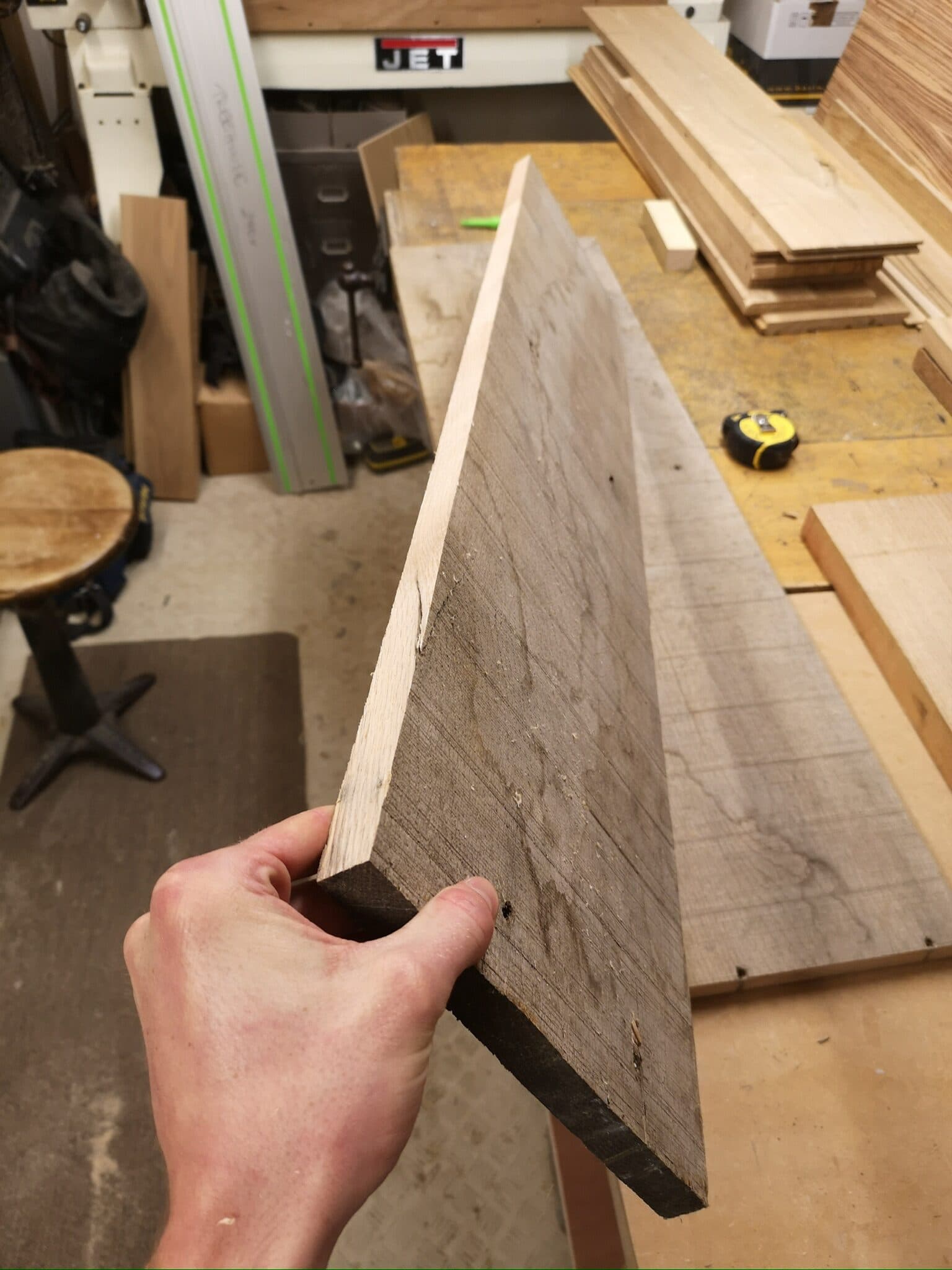A salvaged oak floorboard held up over the bench