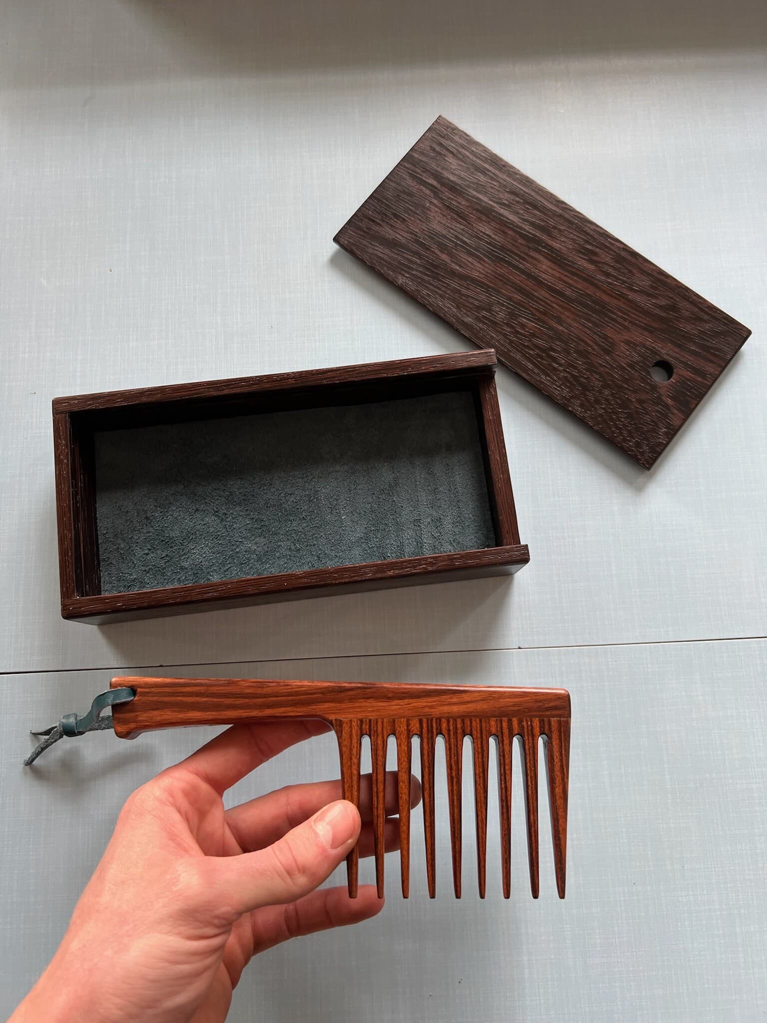 The comb in hand beside its open wenge case